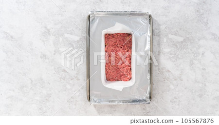 Flat lay. Preparing classic meatloaf in a loaf pan lined with parchment paper. 105567876