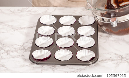Step by step. Baking chocolate cupcakes. Scooping chocolate cupcake batter into a cupcake pan. 105567935