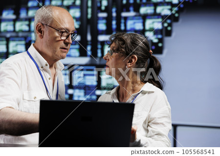 Certified aged developers working to maintain uptime in high tech facility. Trained IT programmers brainstorming solutions to data center server cabinets crashing, trying to fix components 105568541