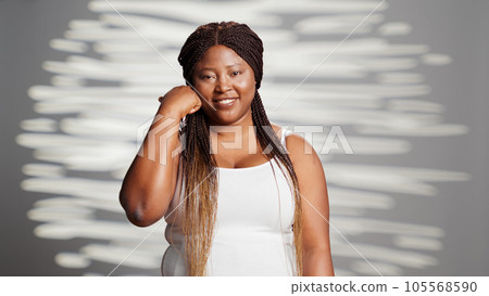 Cheerful young person creating beauty campaign ad in studio, feeling flawless and confident on camera. Glamorous elegant embracing imperfections and promoting self love and confidence. 105568590