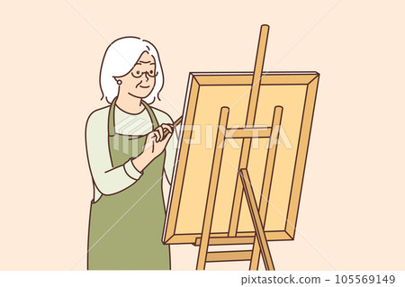 Elderly woman artist stands near easel and draws picture enjoying creative hobby after retiring 105569149