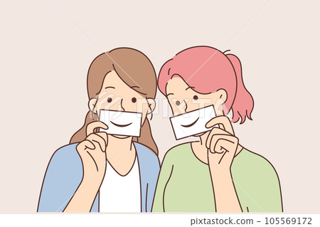 Two women with fake smiles hold papers with drawn emotions and pretend to be happy 105569172