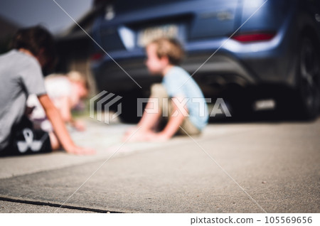 Children sitting on a driveway behind a vehicle in a blind spot out of view of the driver. Children sitting on a driveway behind a vehicle in a blind spot out of view of the driver. 105569656