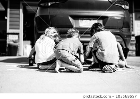 Children sitting on a driveway behind a vehicle in a blind spot out of view of the driver. Children sitting on a driveway behind a vehicle in a blind spot out of view of the driver. 105569657