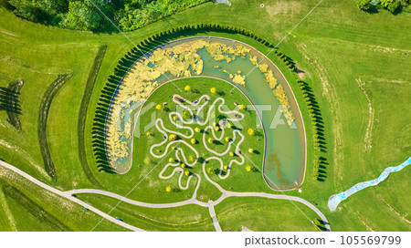 Aerial over tree maze trail in Ariel Foundation Park with curved pond and lily pads_ 105569799