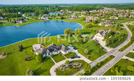 Textured techno road through rich neighborhood property fresh cut grass homes near pond aerial 105569826