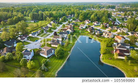 Dark blue pond with housing neighborhood and cul-de-sac suburban homes in summer aerial 105569860