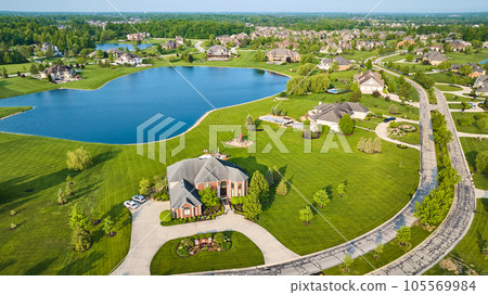 Textured techno road through expensive neighborhood property fresh cut grass homes near pond 105569984