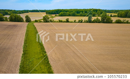 Green patch of land winding its way through barren farmland that is all dirt aerial 105570233
