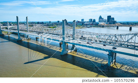 White suspension bridge over murky brown river water Ohio River aerial cityscape background 105570296