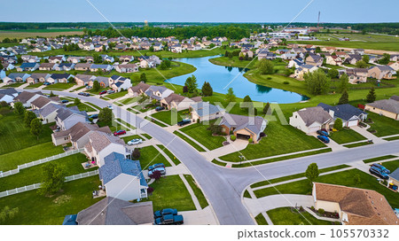 Large pond surrounded by suburban neighborhood HOA houses white picket fence aerial Large pond surrounded by suburban neighborhood HOA houses white picket fence aerial 105570332