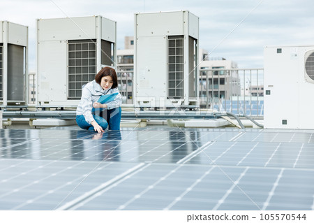 一名女工正在對太陽能電池板進行維護檢查 一名女工正在對太陽能電池板進行維護檢查 105570544