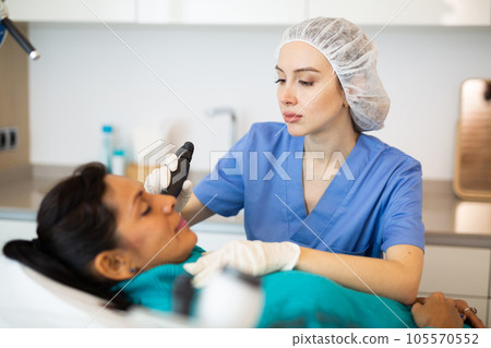 Beautician doing needle-free mesotherapy for hispanic woman Beautician doing needle-free mesotherapy for hispanic woman 105570552