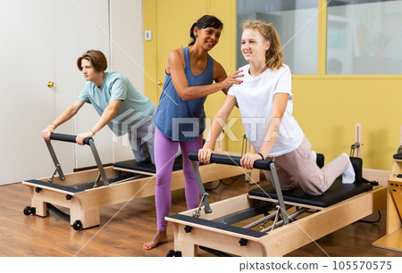 Teens doing pilates exercises with trainer 105570575