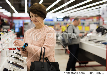 Aged woman choosing digital wristwatches in electronic store Aged woman choosing digital wristwatches in electronic store 105570632
