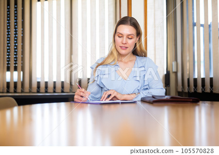 Business woman in office interior filling up documents 105570828