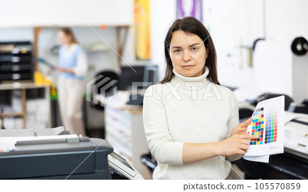 Portrait of positive woman printing office worker with colour test page 105570859