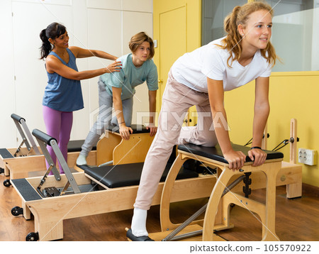 Teens doing pilates exercises with trainer Teens doing pilates exercises with trainer 105570922