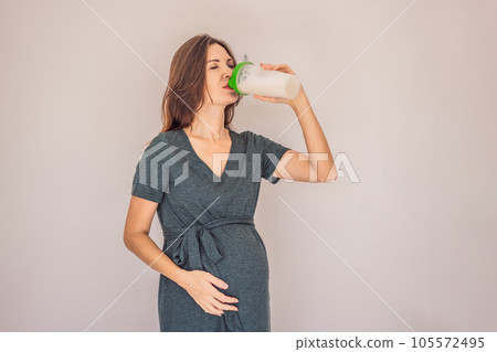 Energetic and fit pregnant woman after 40 enjoying a protein shake for a nourishing boost during her pregnancy journey. Embracing health and wellness for a thriving baby and mom 105572495
