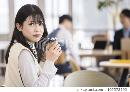 A young woman drinking coffee in a stylish office cafe space 105572593