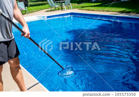 Poy using a skimmer to collect leaves out of a swimming pool 105573350