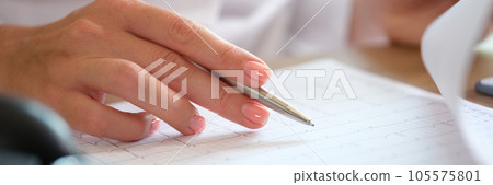 Female cardiologist checking cardiogram of patient with pen in her hand. 105575801