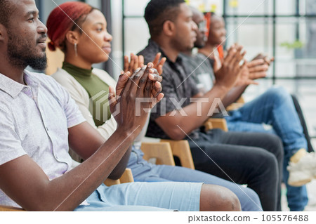 Group of men and women sit in a row and applaud a man who puts forward an idea or says something. Group of men and women sit in a row and applaud a man who puts forward an idea or says something. 105576488