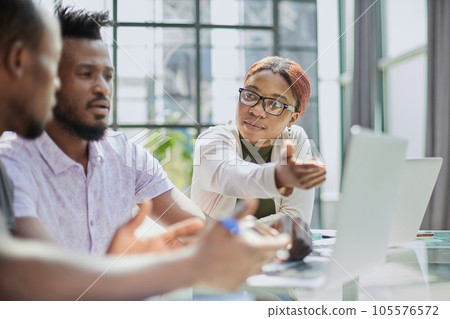 Group of business people in casual wear sitting together at the table and looking at the laptop Group of business people in casual wear sitting together at the table and looking at the laptop 105576572