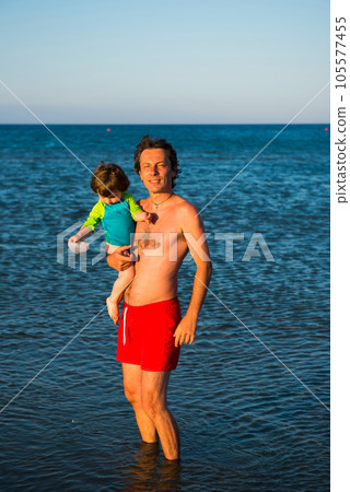 Father and daughter playing together in the sea water 105577455
