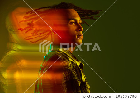 Portrait of young african man posing against gradient green background in neon light. Mixed light effect. Youth culture Portrait of young african man posing against gradient green background in neon light. Mixed light effect. Youth culture 105578796