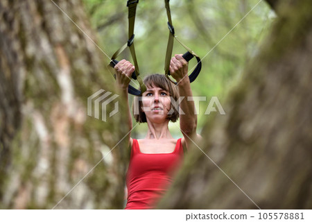 Woman doing arms biceps curl training with trx fitness straps 105578881
