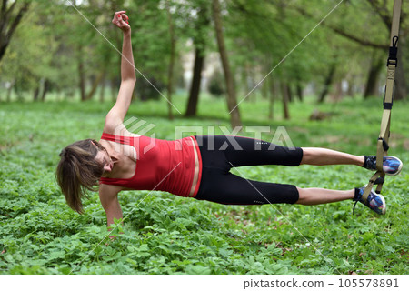 Beautiful young woman doing TRX exercise with suspension trainer sling in the outdoors 105578891