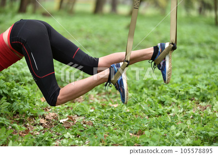 Beautiful young woman doing TRX exercise with suspension trainer sling in the outdoors 105578895