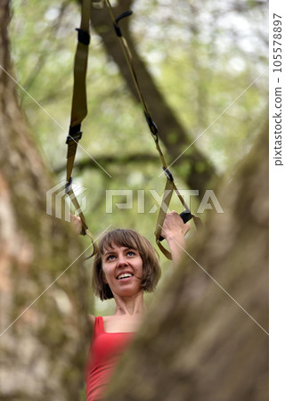 Woman doing arms biceps curl training with trx fitness straps Woman doing arms biceps curl training with trx fitness straps 105578897