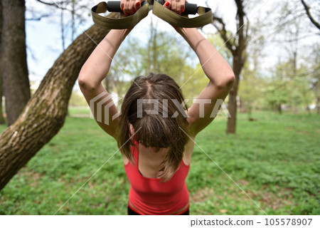 Young attractive woman does body stretching with trx fitness straps 105578907