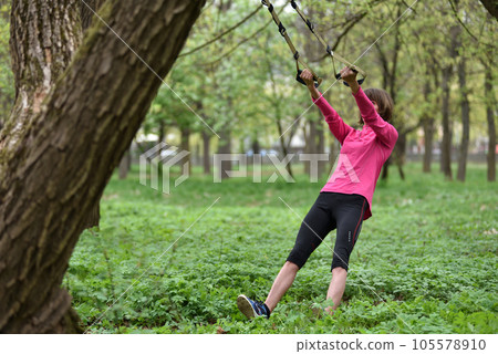 Woman doing arms biceps curl training with trx fitness straps 105578910