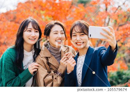 三名女性在秋葉背景下用智能手機拍照 三名女性在秋葉背景下用智能手機拍照 105579674