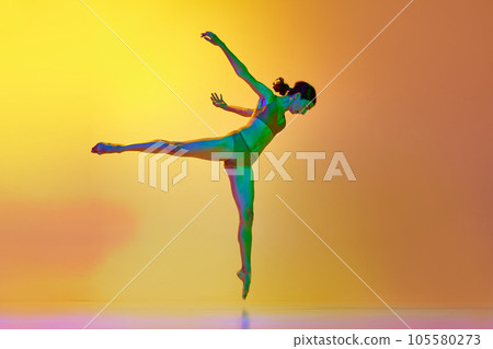 Young talented woman dancing contemp against gradient yellow orange background in neon light. Slim body Young talented woman dancing contemp against gradient yellow orange background in neon light. Slim body 105580273