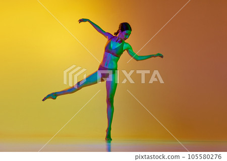 Full-length image of young woman, professional dancer in motion, dancing in underwear against gradient yellow orange background in neon light Full-length image of young woman, professional dancer in motion, dancing in underwear against gradient yellow orange background in neon light 105580276