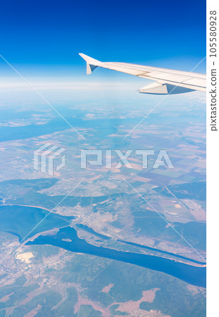 Aerial view from airplane window above green ground. View from the airplane window with beautiful clouds at sunrise 105580928
