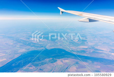 Aerial view from airplane window above green ground. View from the airplane window with beautiful clouds at sunrise 105580929
