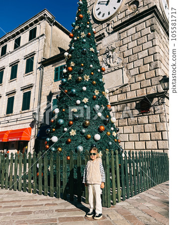 Little girl posing near the Christmas tree near the ancient building 105581717