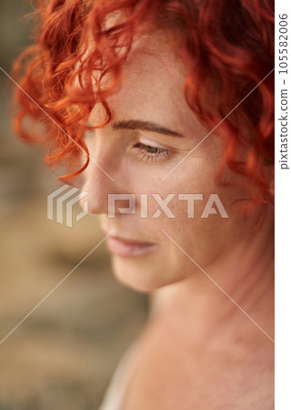 Portrait middle age woman with red curly hair looking at sea. Summer holiday rest 105582006