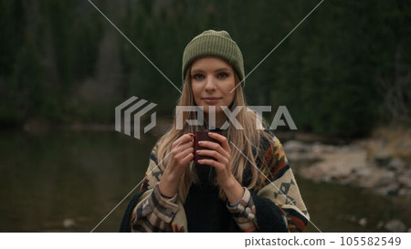 Portrait of tourist girl near mountain river, drinking coffee against the backdrop of mountains Portrait of tourist girl near mountain river, drinking coffee against the backdrop of mountains 105582549