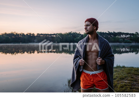 Serious guy at the forest near the water and preparing for the swimming in the cold lake at morning 105582583
