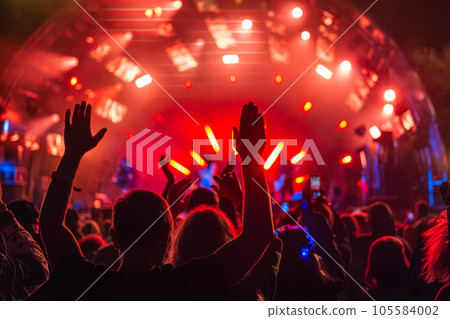 Fans with raised arms against glowing stage 105584002