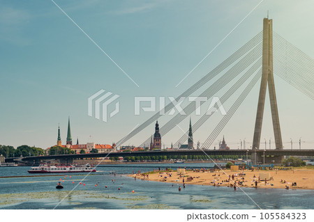 View of  beach on the Daugava river and old town of Riga, Riga castle and bridge over the Daugava River in Riga city, Latvia. 105584323