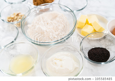 Measured ingredients in glass mixing bowls to bake lemon poppy seed muffins. 105585485