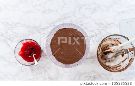 Flat lay. Covering chocolate cake with a crumb layer of chocolate buttercream frosting. 105585528