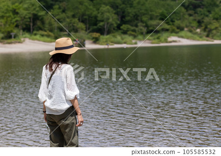 高原湖邊漫步的戴草帽女子 105585532